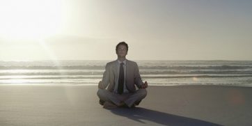 man meditating on beach